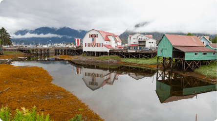 Houses lined up in front of a small body of water with clouds hovering over them